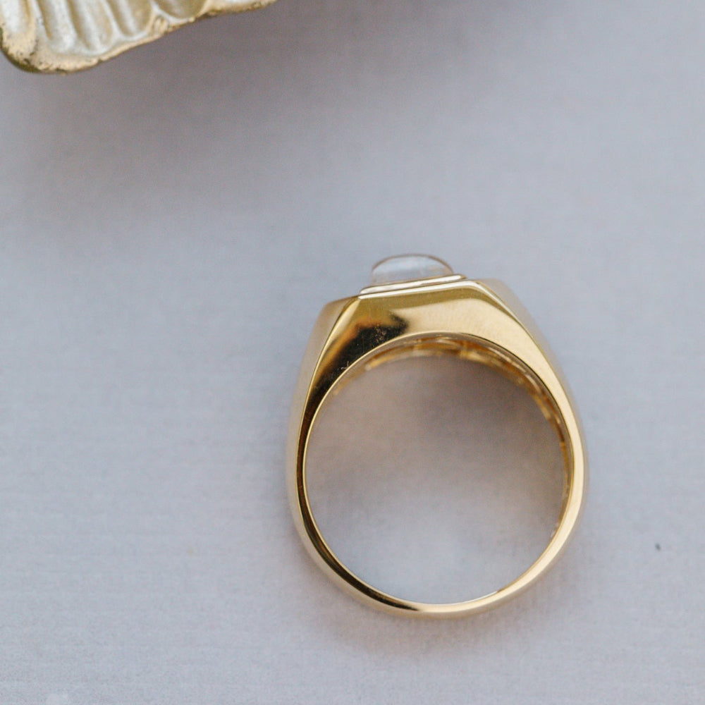 Gold ring with a small stone on a light gray surface
