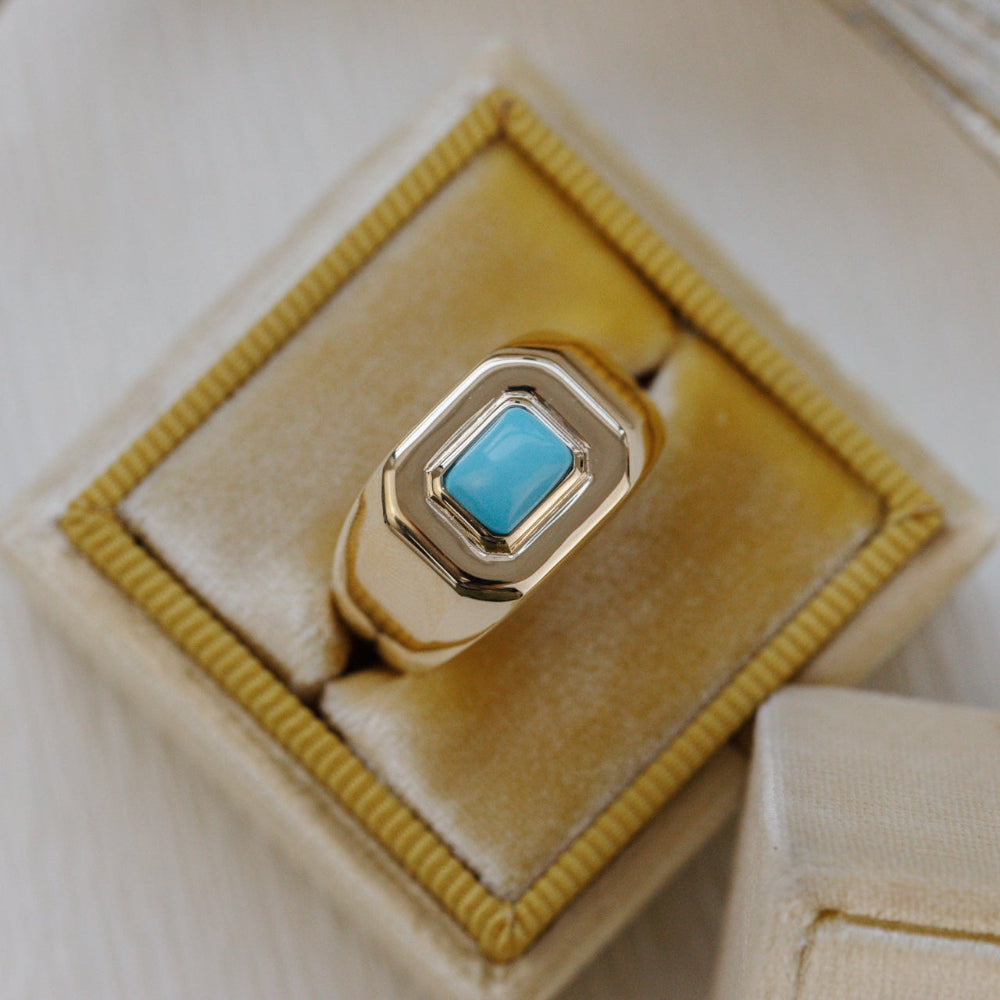 Gold ring with a turquoise stone on a yellow cushion