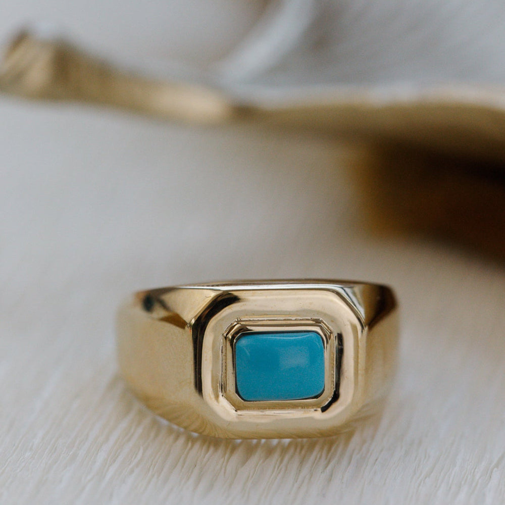 Gold ring with a blue stone on a light background