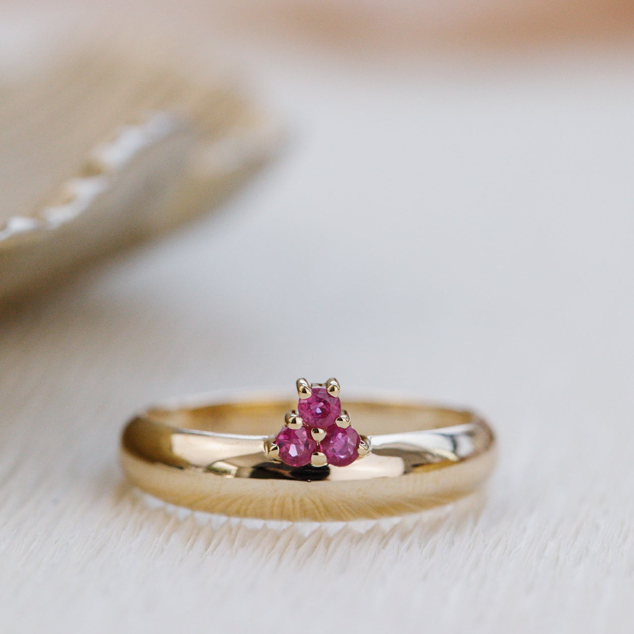 Gold ring with ruby gemstones on a soft background