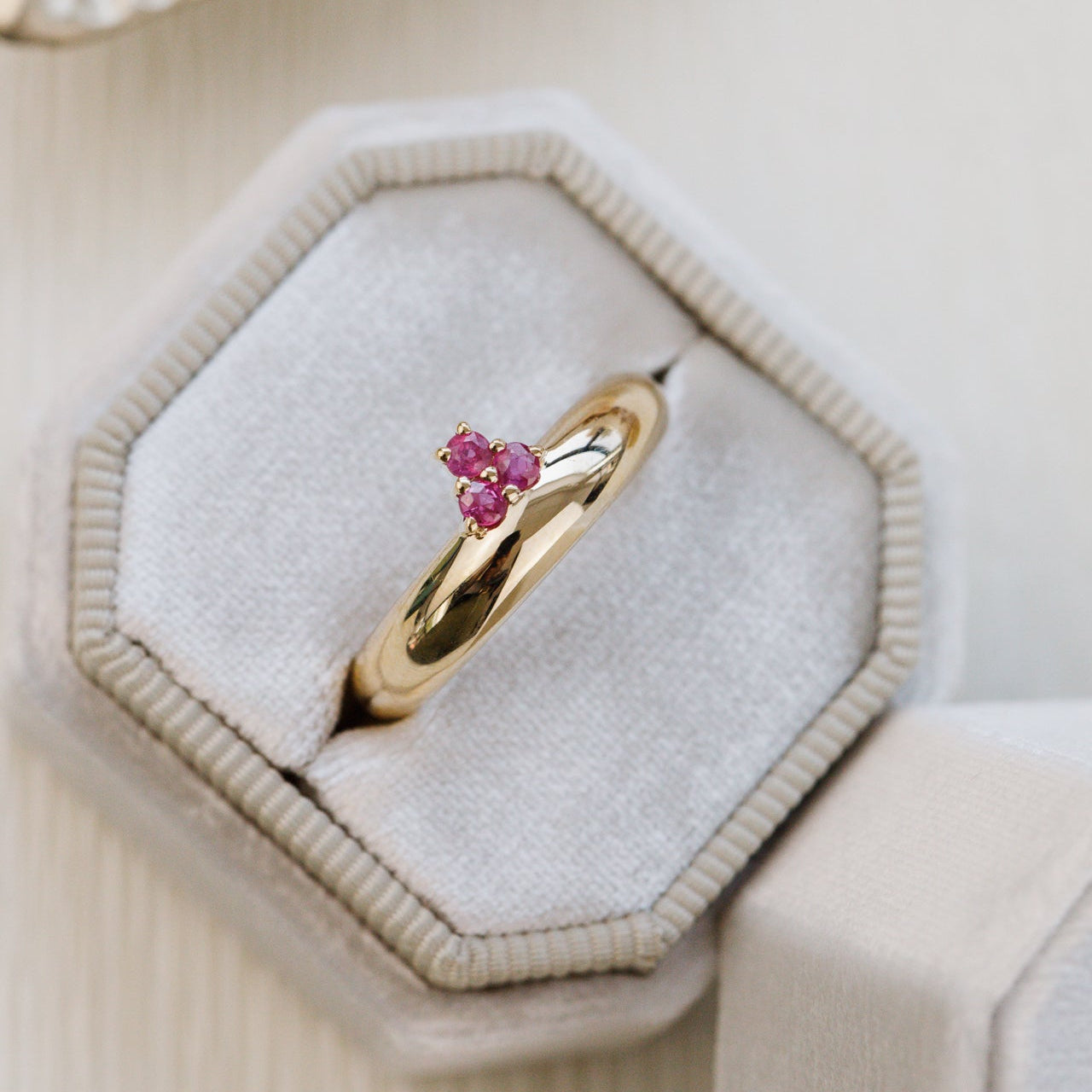 Gold ring with ruby gemstones on a hexagonal jewelry box