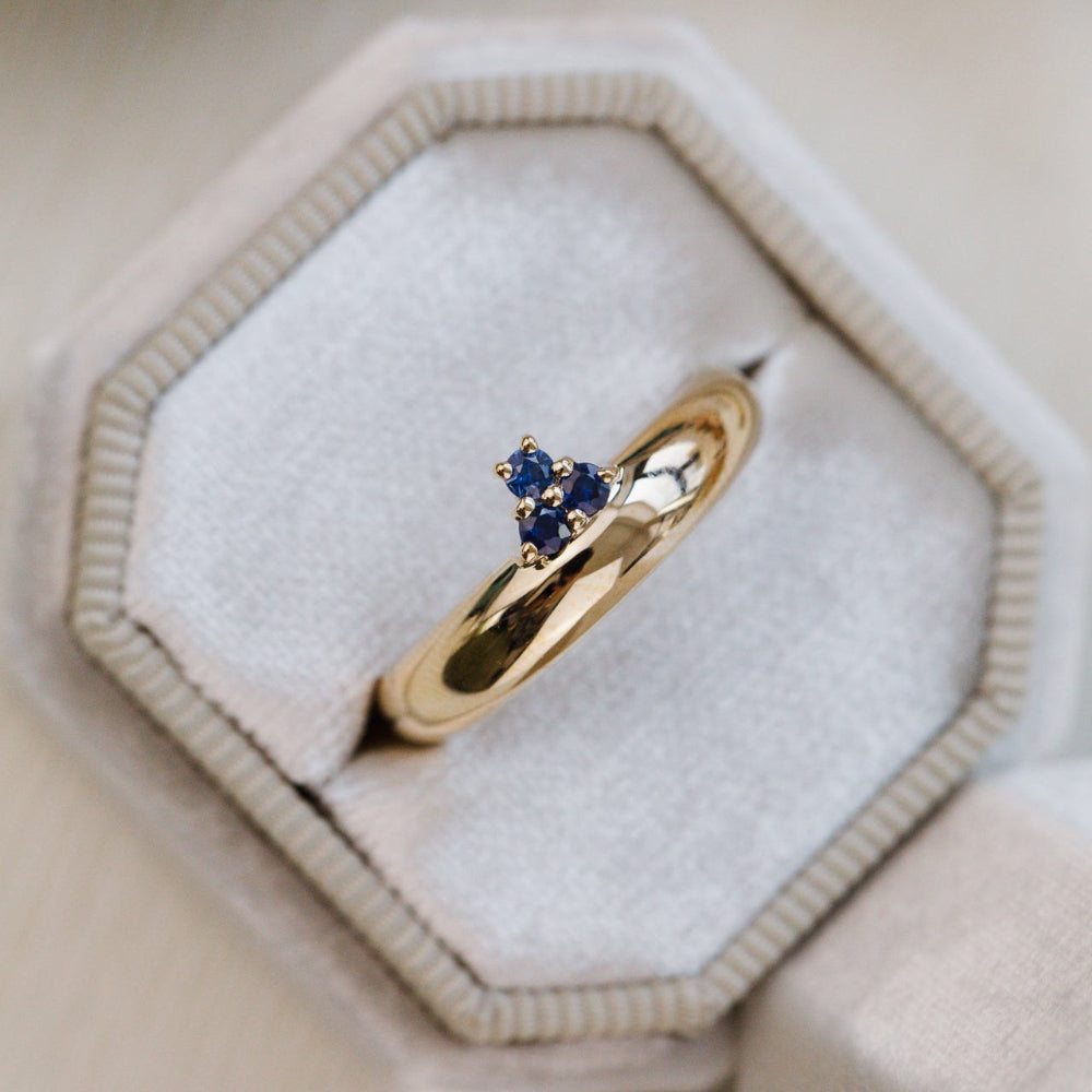 Gold ring with blue gemstones on a soft white background