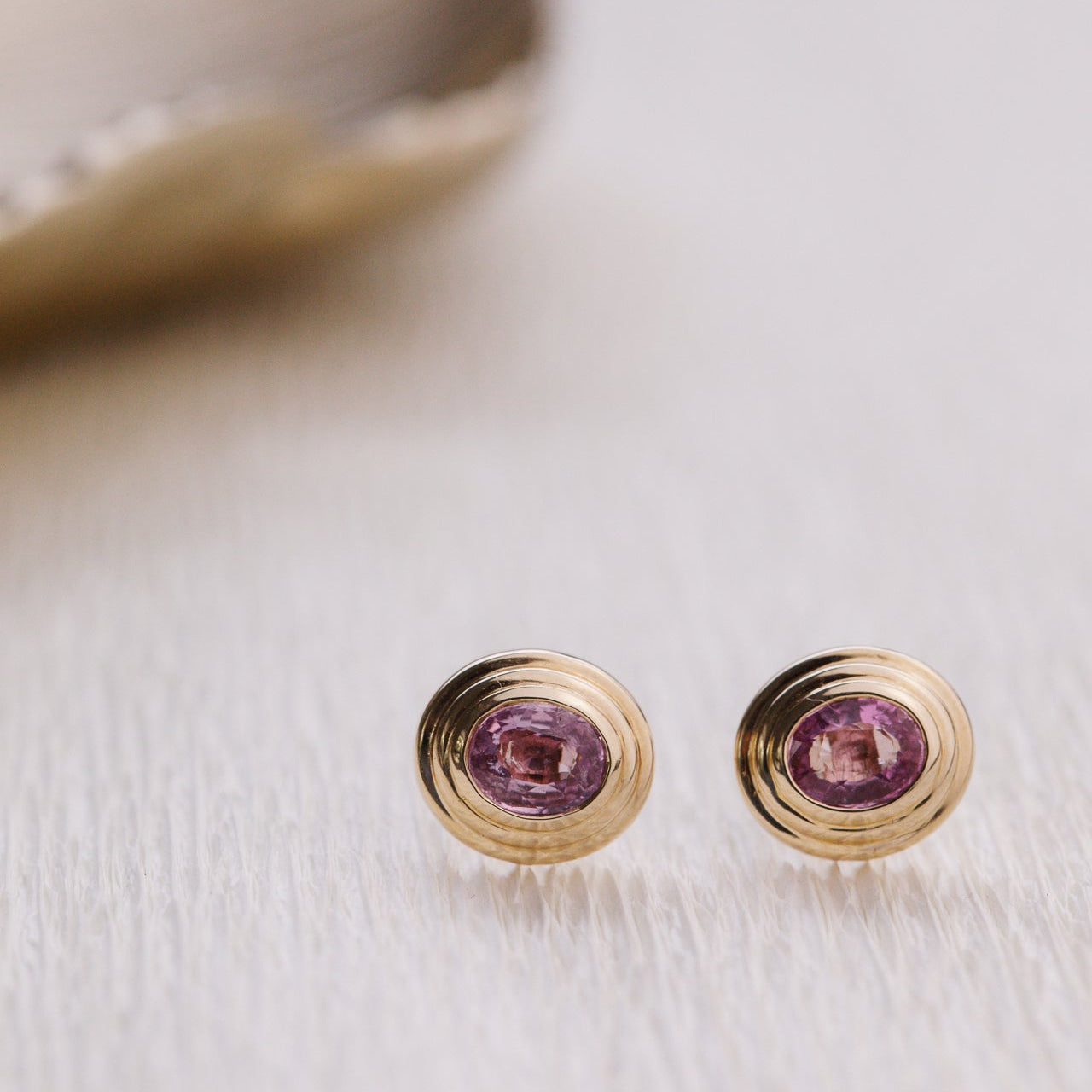 Gold earrings with pink sapphires gemstones on a light background
