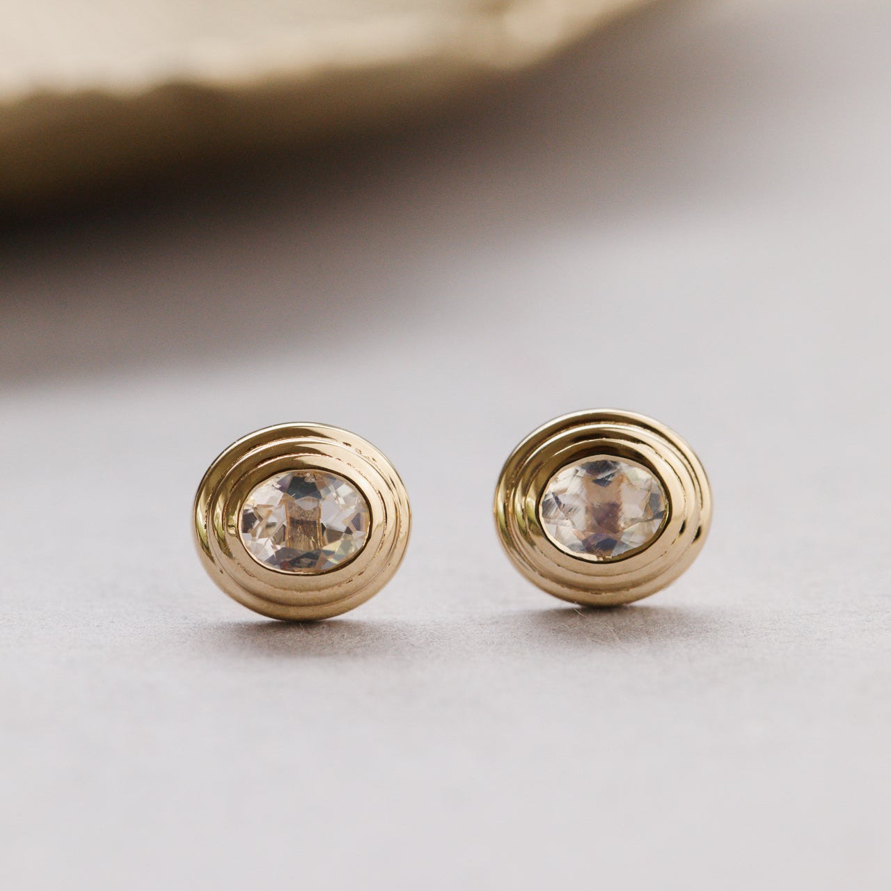 Gold earrings with clear gemstones on a light background