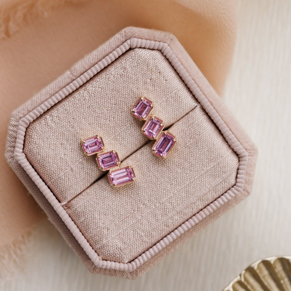 Pink gemstone earrings in a jewelry box on a soft beige background