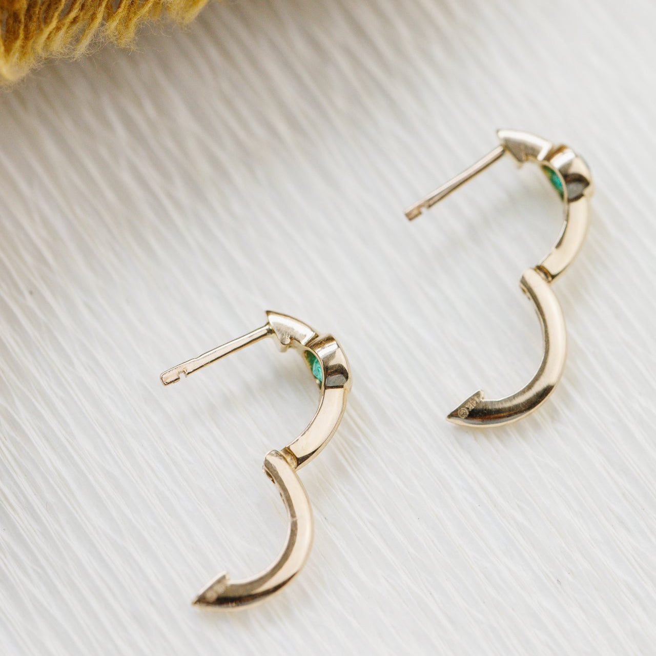 Gold hoop earrings on a textured white surface