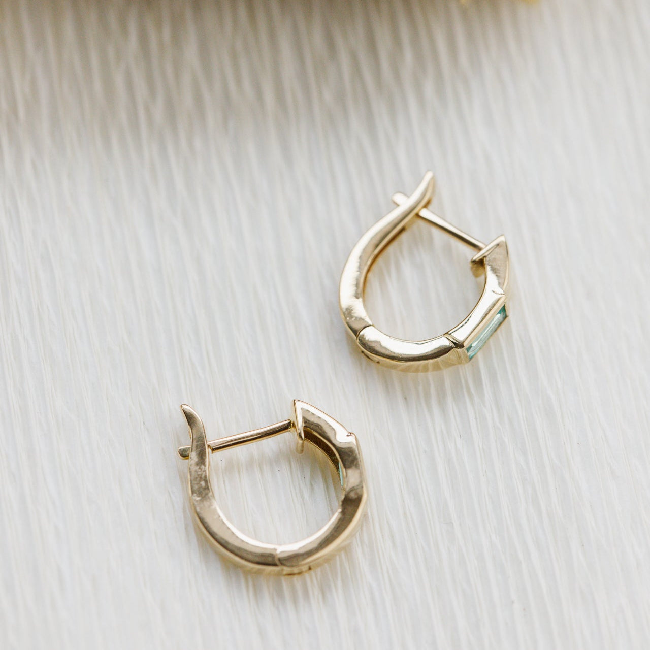 Gold hoop earrings on a light wooden surface