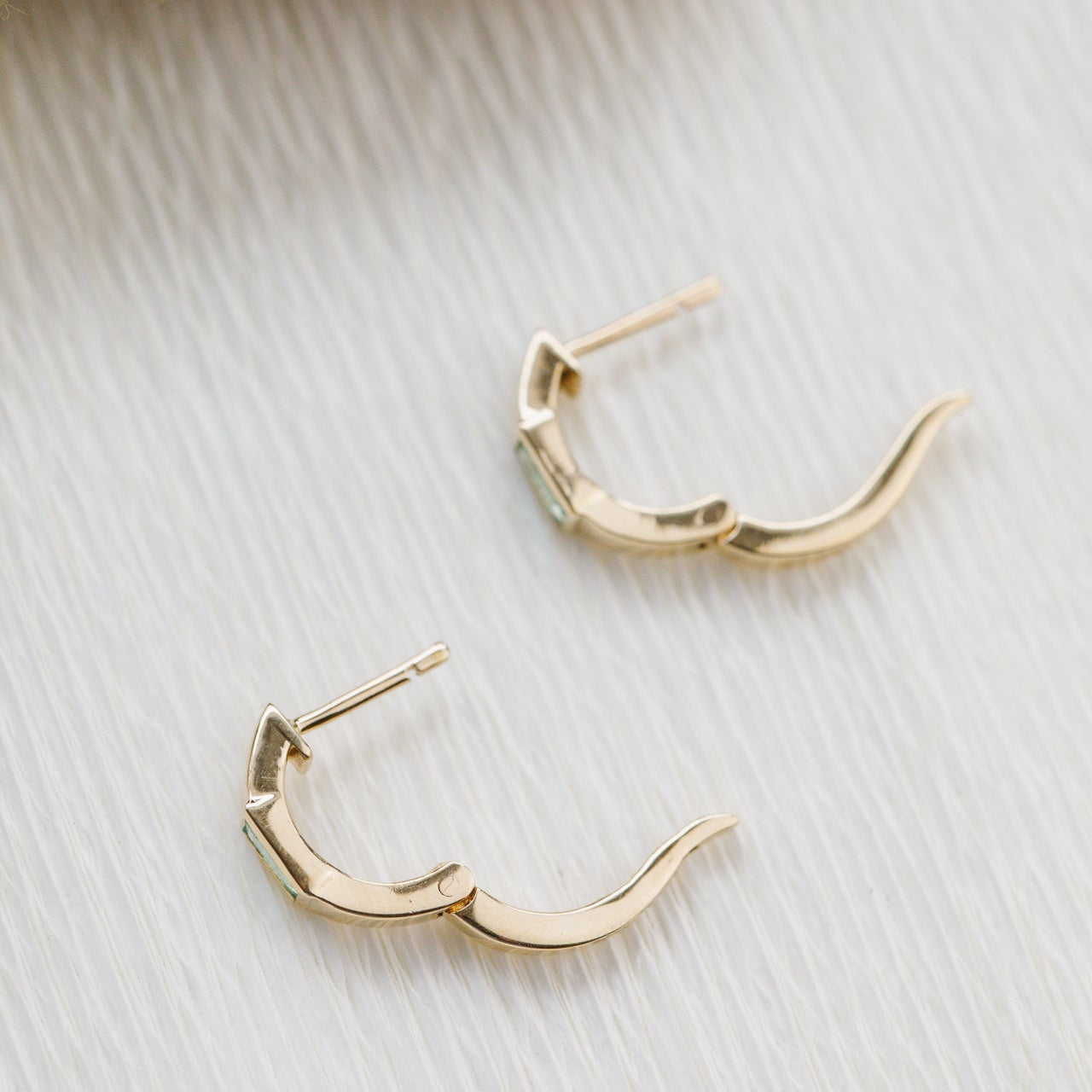 Gold hoop earrings on a light wooden surface