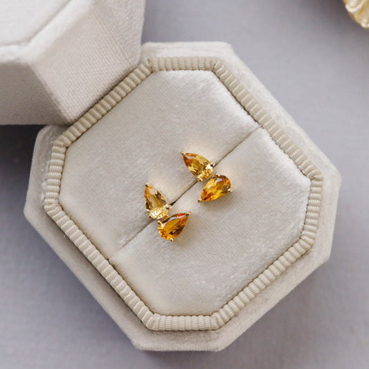 Pair of yellow citrine gemstone earrings on a beige jewelry display box.