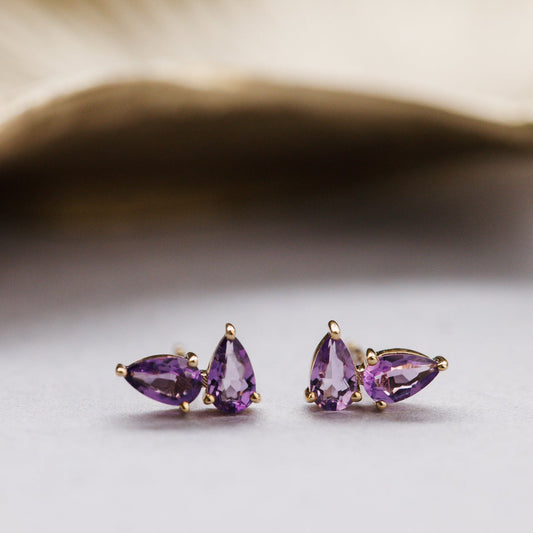 Pair of purple pear earrings on a light background
