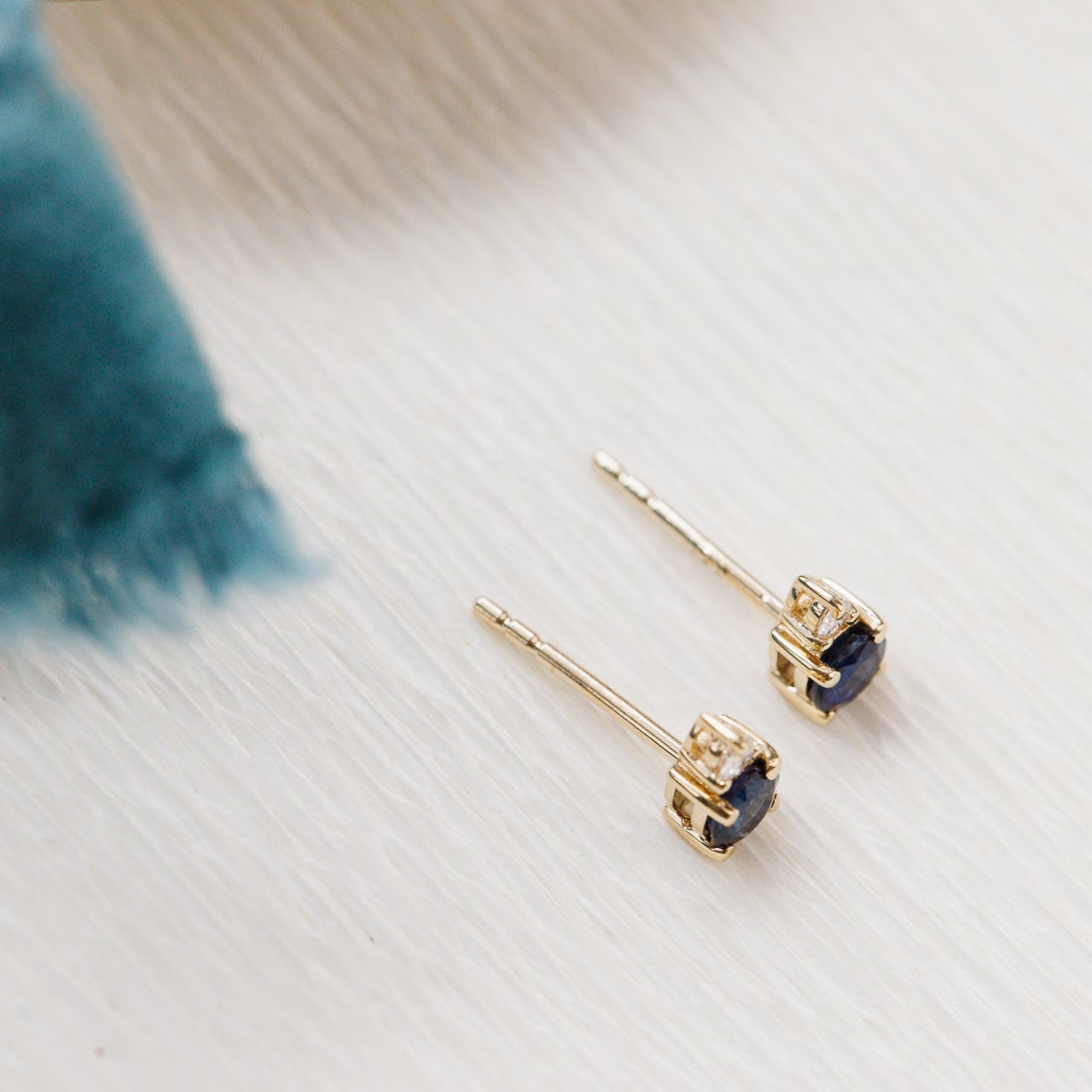 Gold earrings with blue sapphires gemstones on a light wooden surface