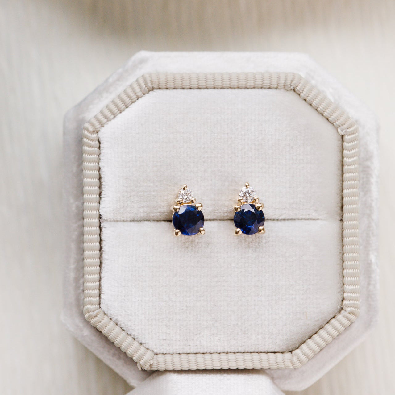 Pair of sapphire earrings on a white jewelry display box