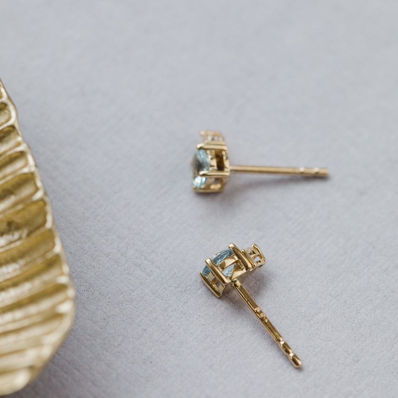 Gold earrings with gemstones on a light gray background