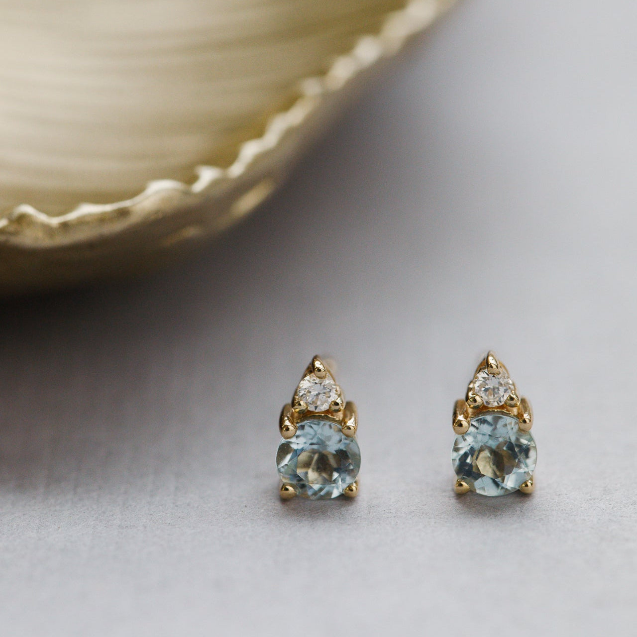Gold earrings with blue aquamarine gemstones on a light background