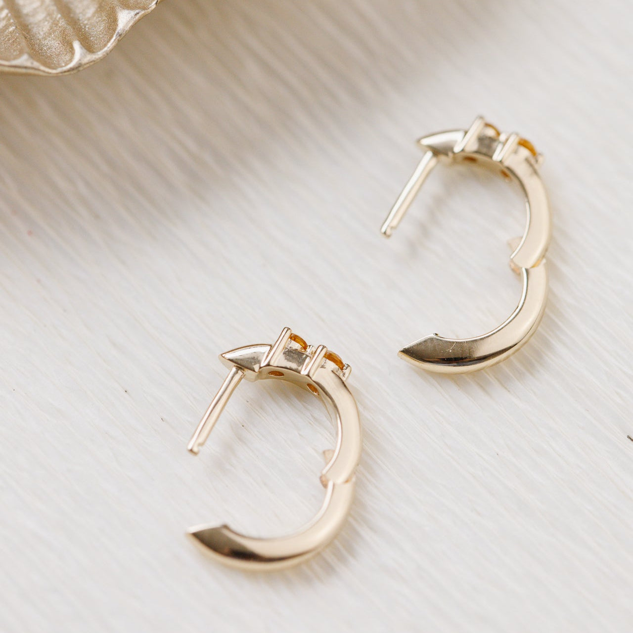 Gold hoop earrings on a textured beige surface