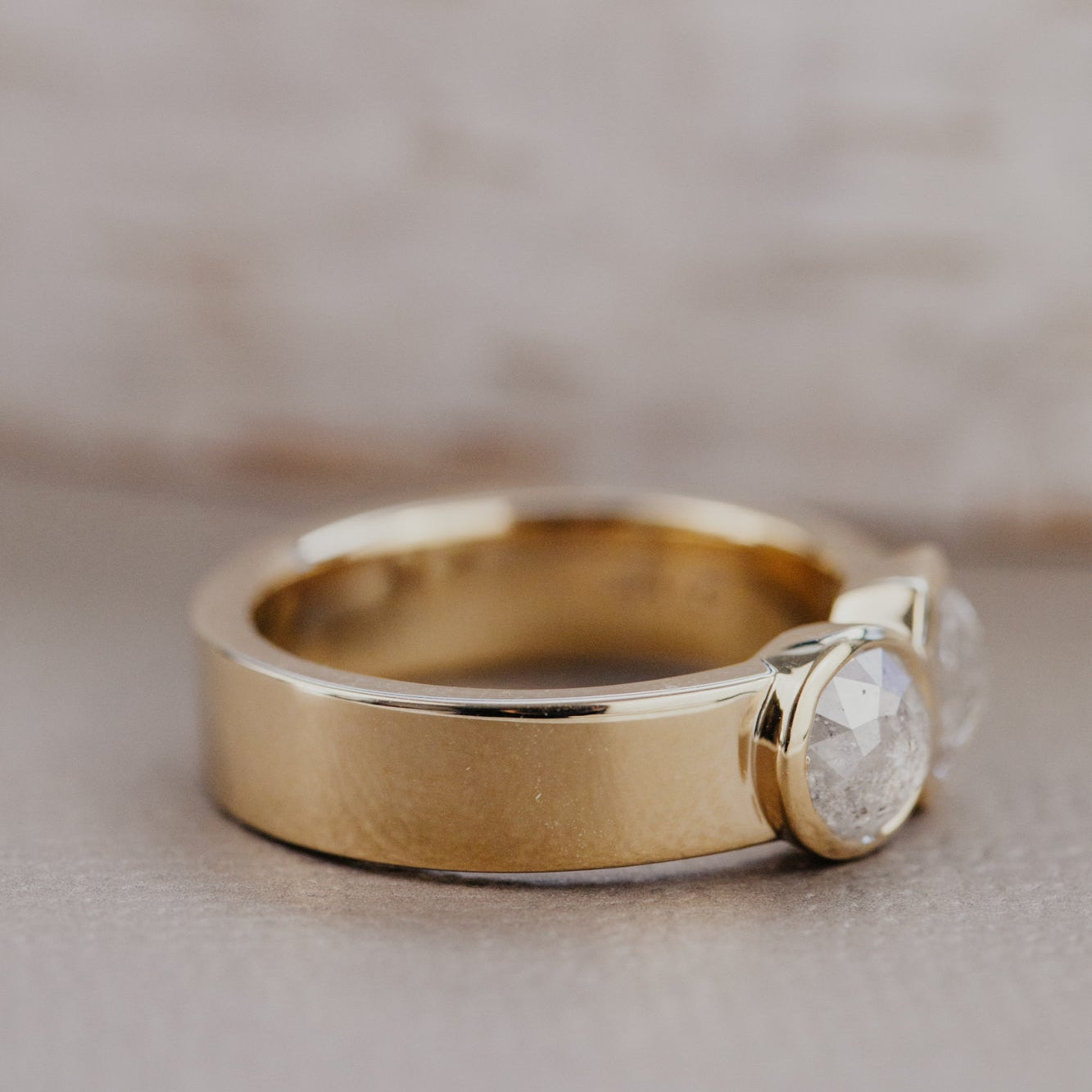 Gold ring with a rustic diamond on a neutral background.