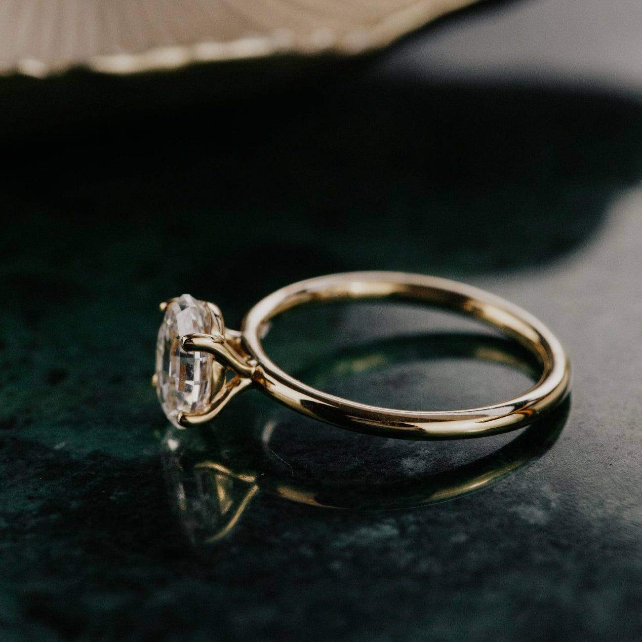 Gold ring with a oval diamond on a dark surface.