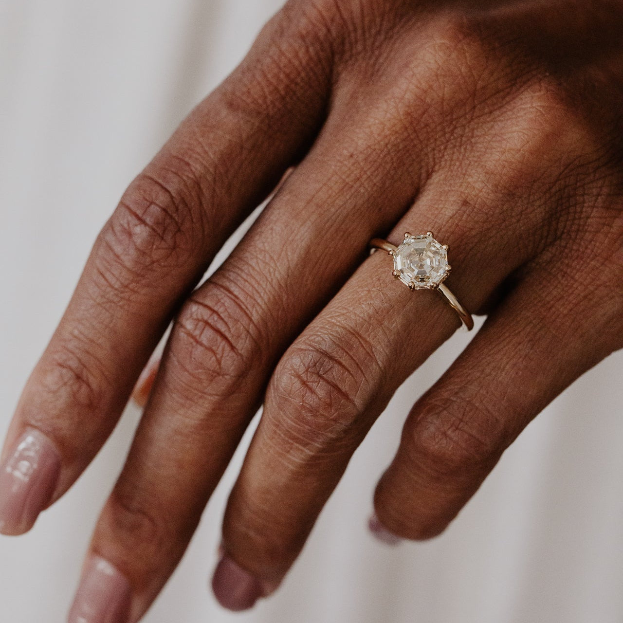Hand wearing a Octagon champagne diamond ring on a neutral background.