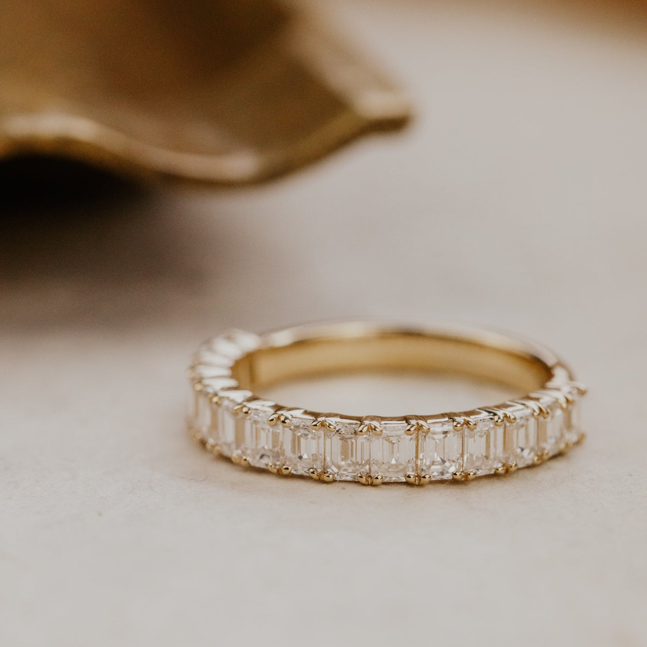 The Amara emerald cut diamond band on a white surface.