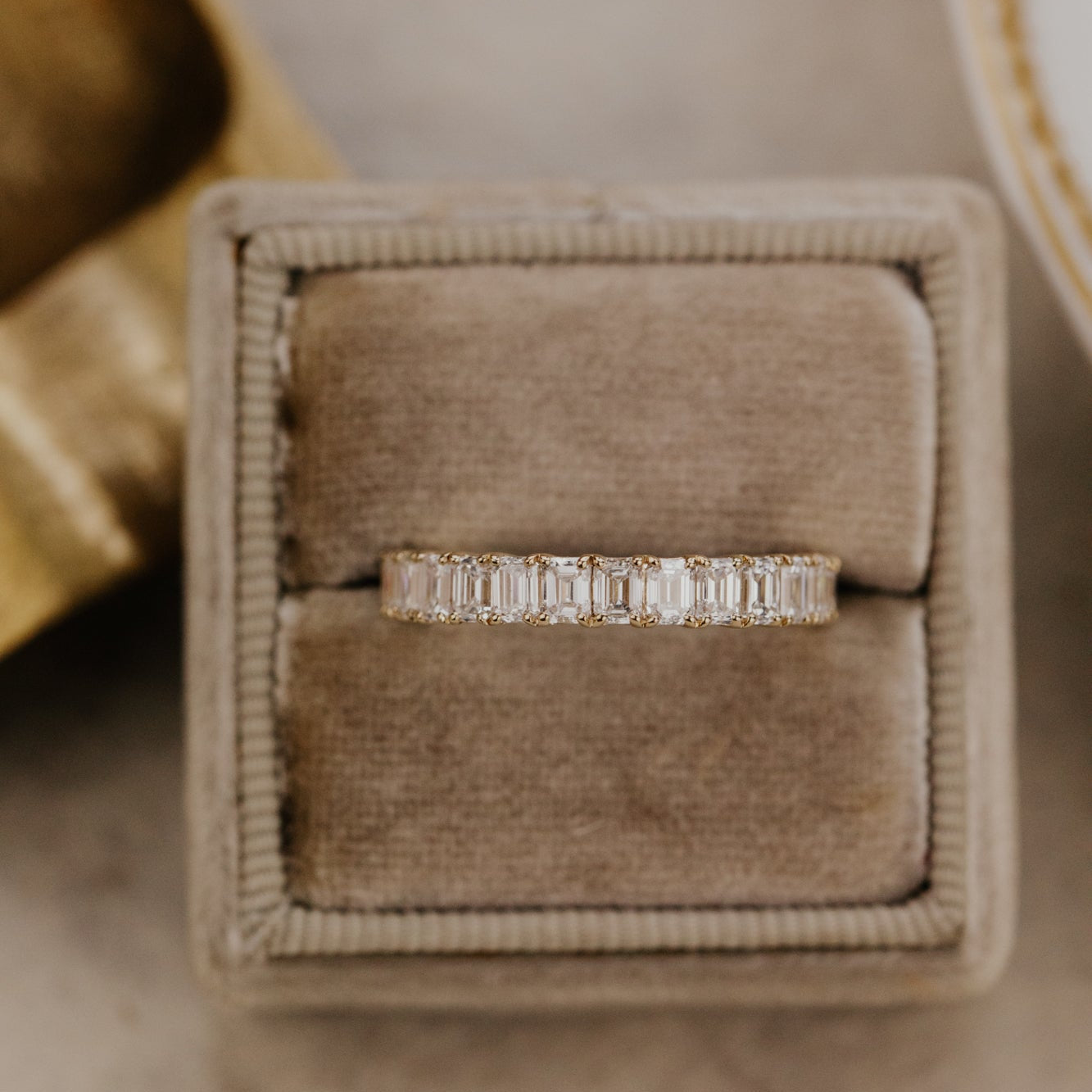 The mini Amara emerald cut diamond band in a brown velvet ring box.