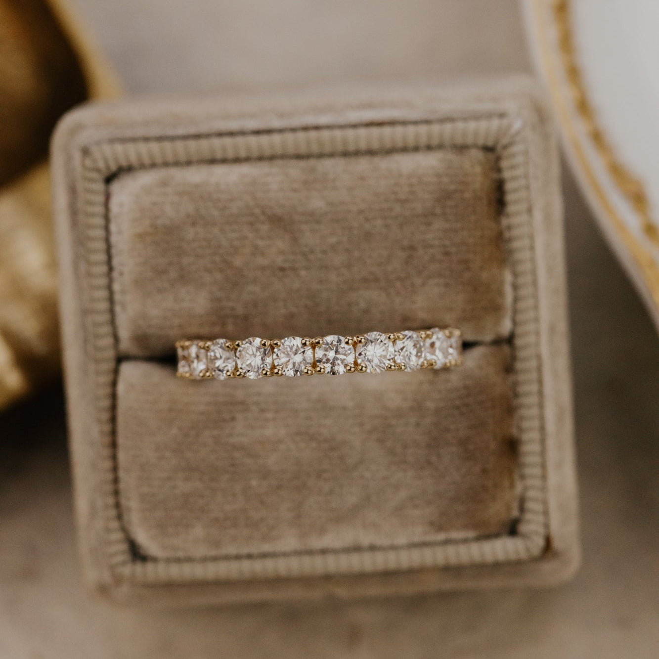 The mini Amara round diamond wedding band placed in a brown velvet ring box.