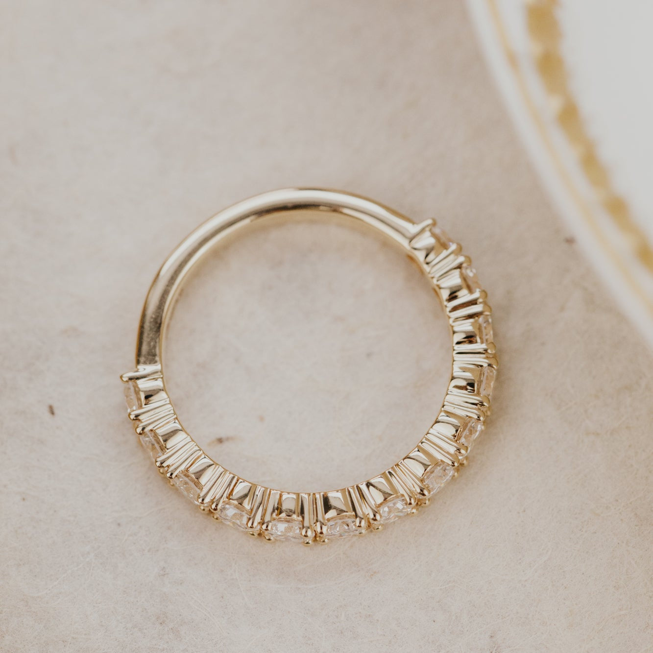 Top down view of the mini Amara round band in 14k yellow gold on a white surface.