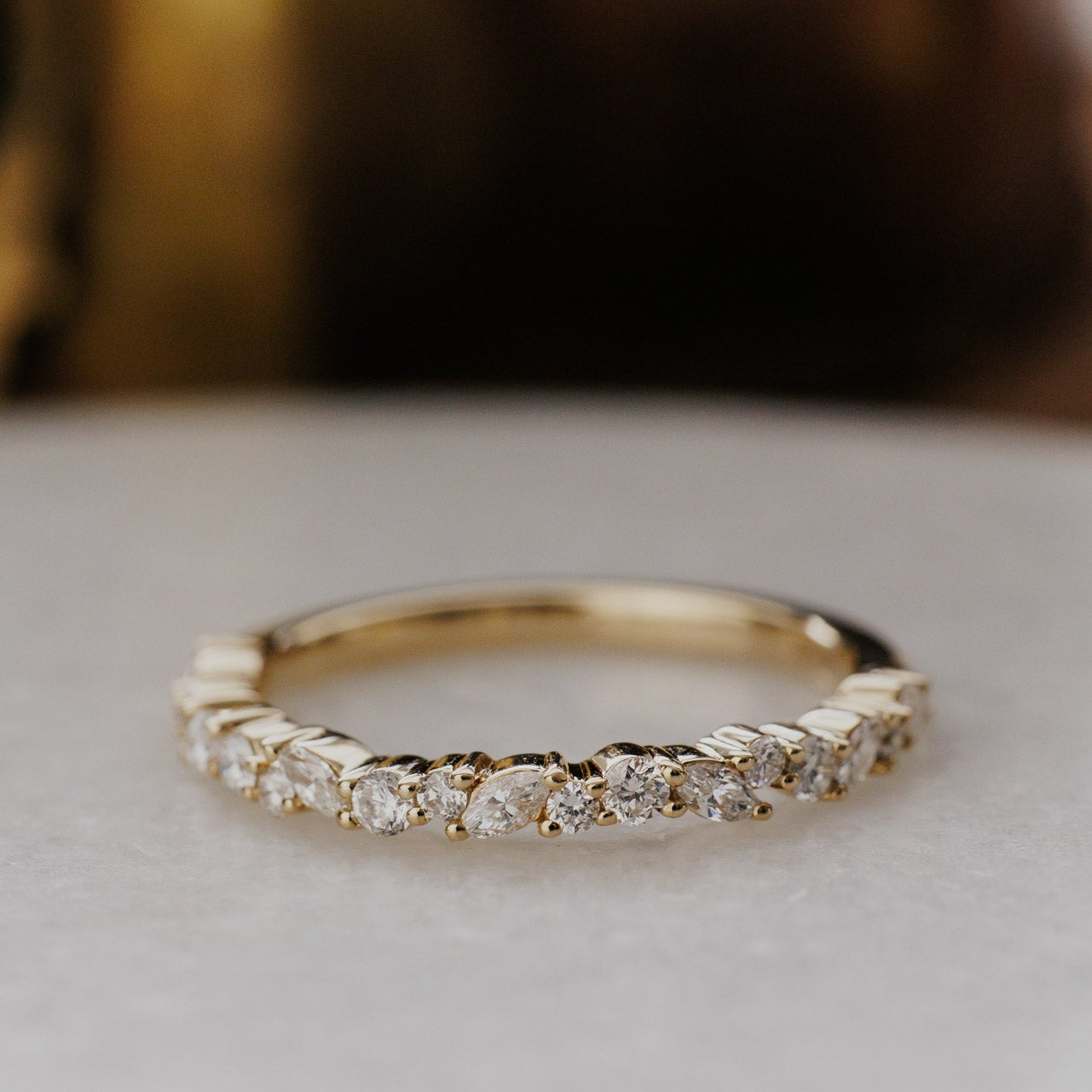 Gold mini Natalie wedding band with diamonds on a light background.