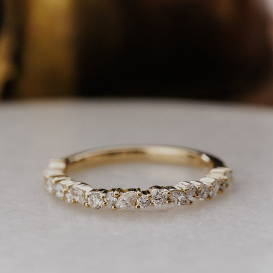 Gold mini Natalie wedding band with diamonds on a light background.