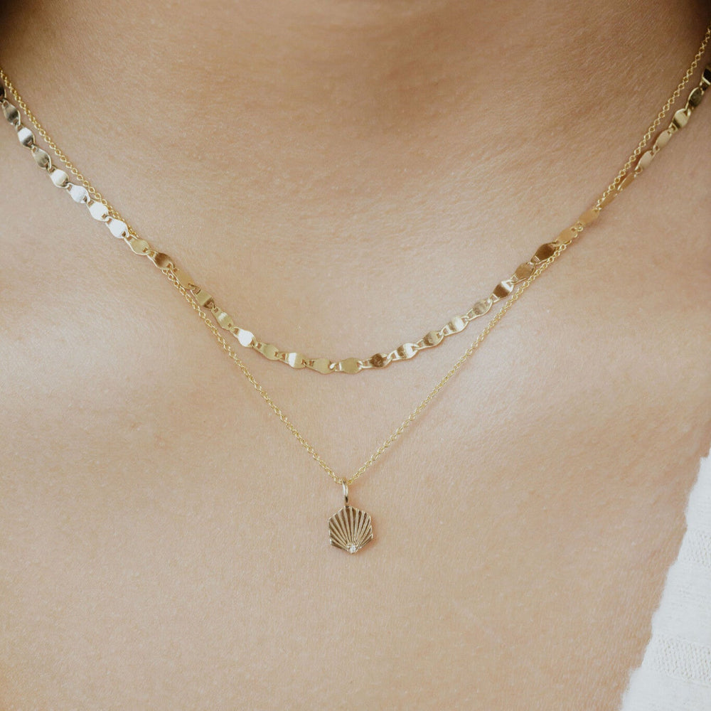 Gold necklace with a small charm on a person's neck