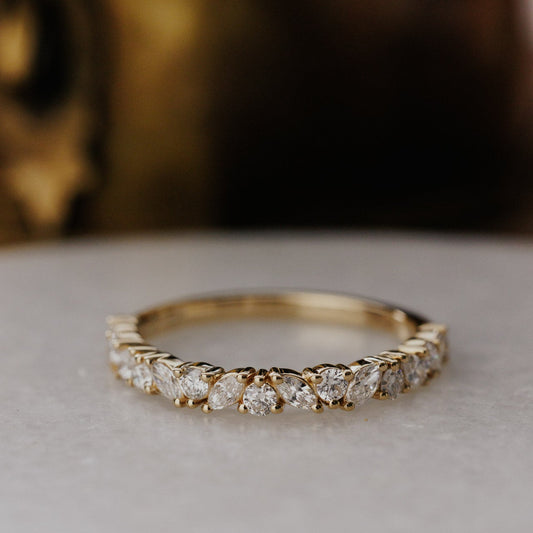 Gold wedding band with diamonds on a neutral background.