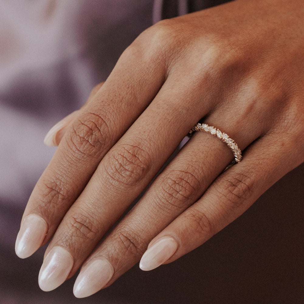 Close-up of a hand wearing the Natalie diamond wedding band with a blurred background.