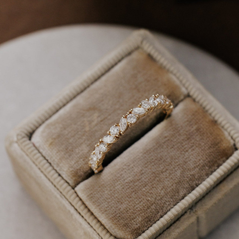 Natalie wedding band with diamonds on a beige velvet cushion in a jewelry box.