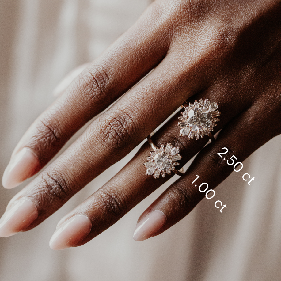 Hand wearing two round diamond rings with visible carat weight on a neutral background