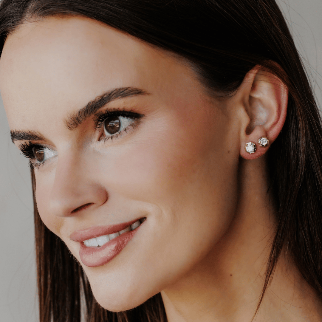 14k gold diamond earrings set in prongs showcased on a model with two carat sizes featured.