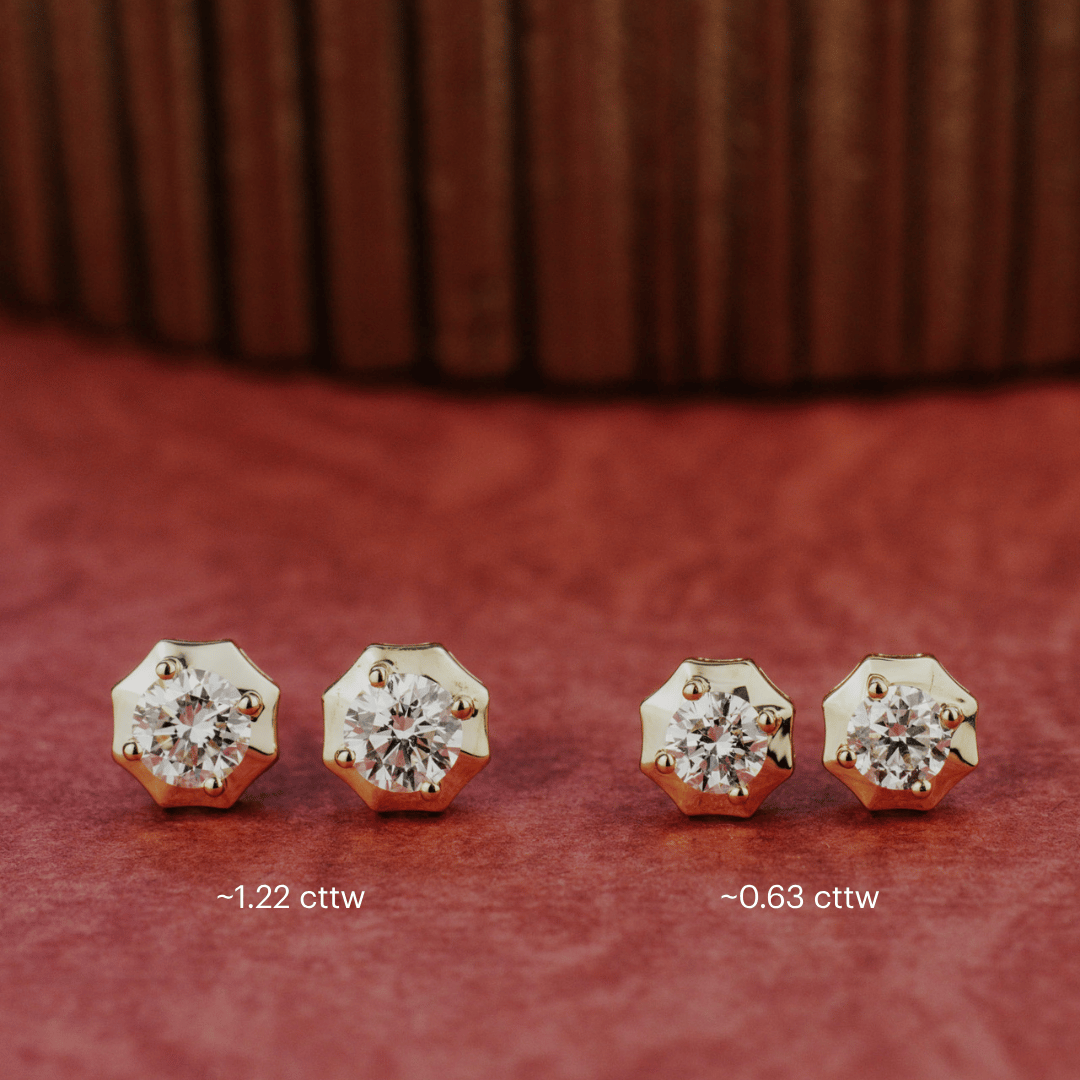 14k gold diamond earrings set in prongs showcased on a textured red surface. Showcasing two different carat sizes. 
