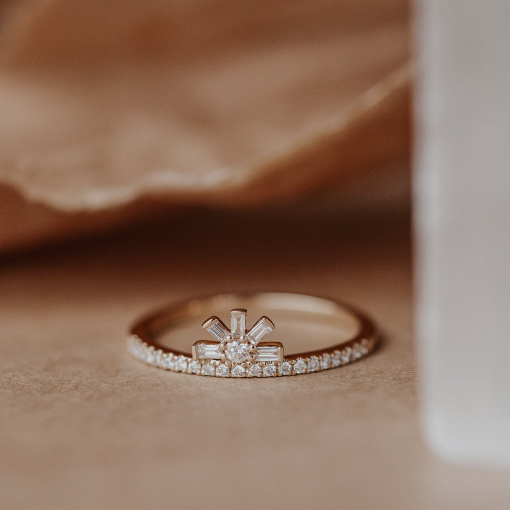 Rose gold wedding band with diamond accents on a soft brown fabric background.