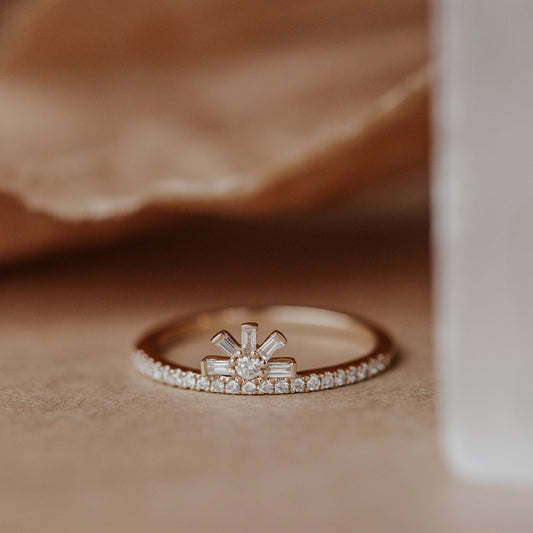 Rose gold wedding band with diamond accents on a soft brown fabric background.