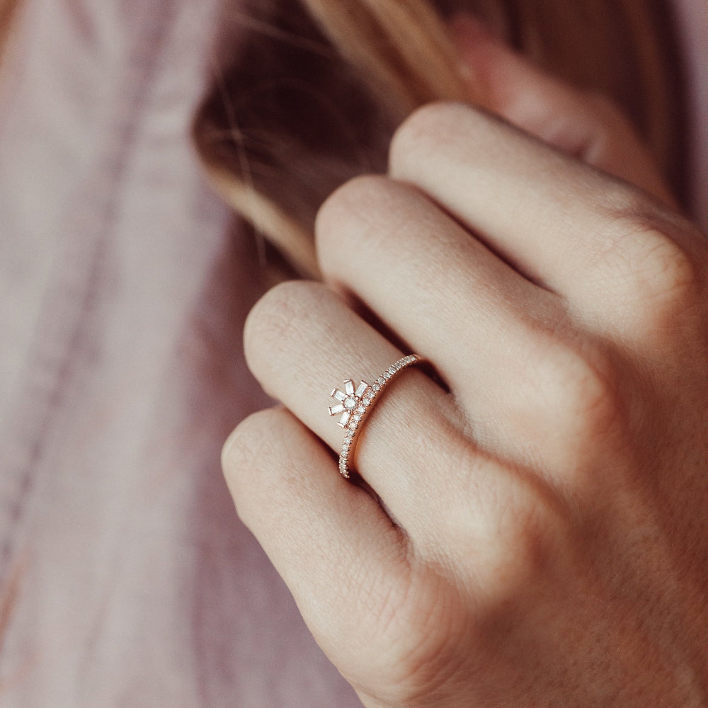 Close-up of a hand wearing a rose gold diamond wedding band with a soft background.
