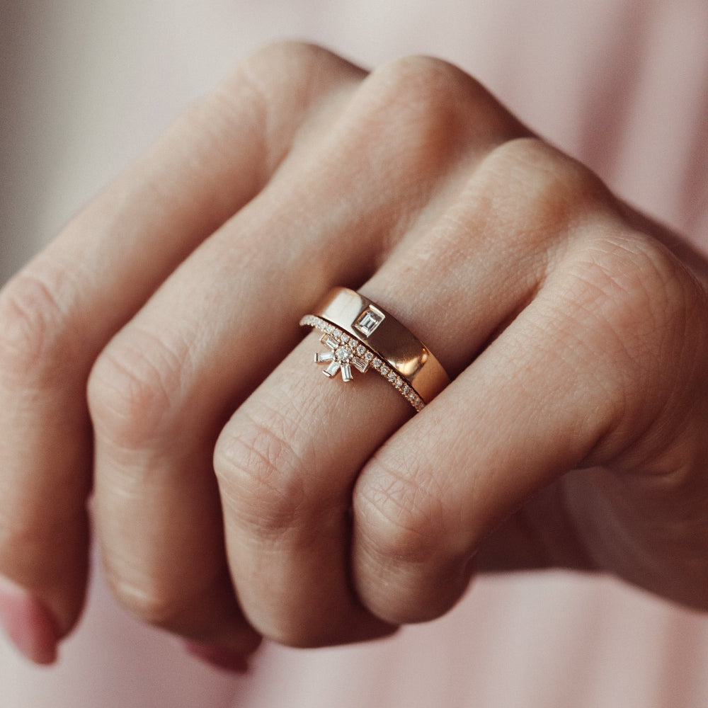 Close-up of a hand wearing two wedding bands with a soft background.