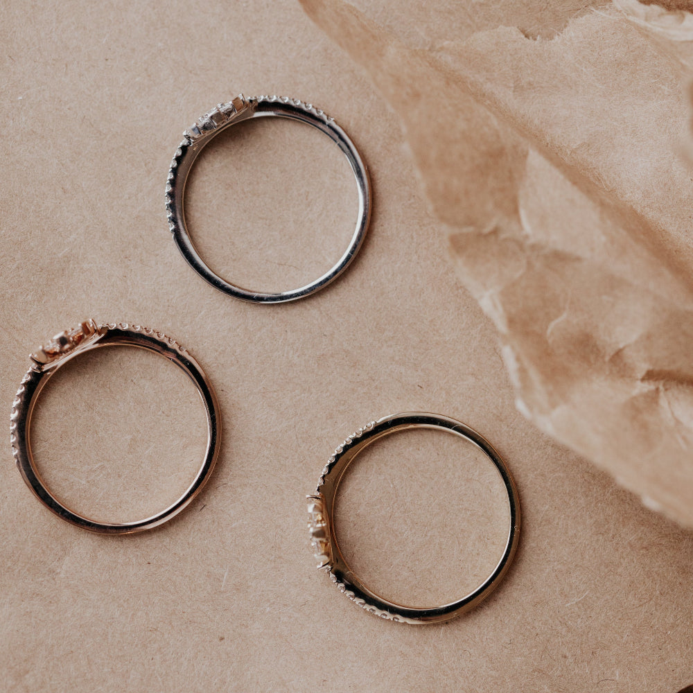 Three rings on a textured beige surface.