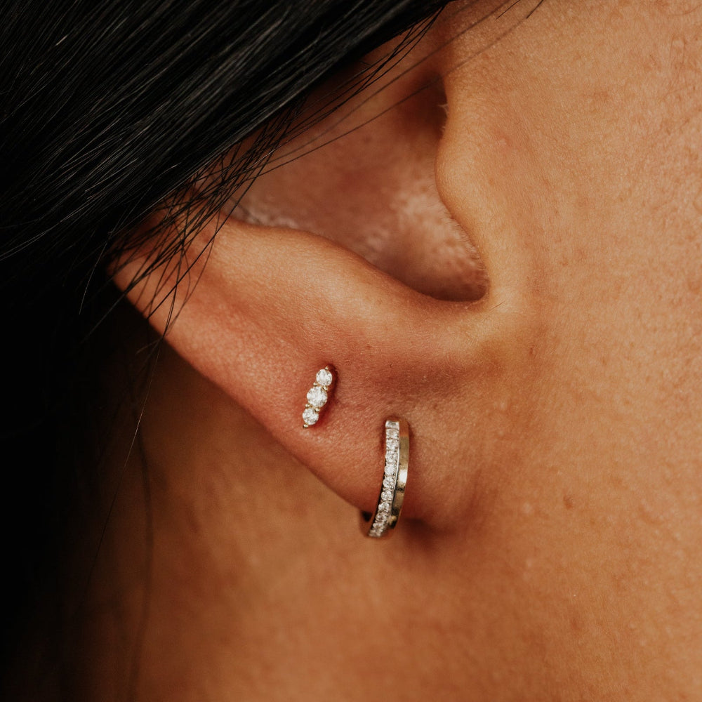 Close-up of an ear wearing two diamond earrings.