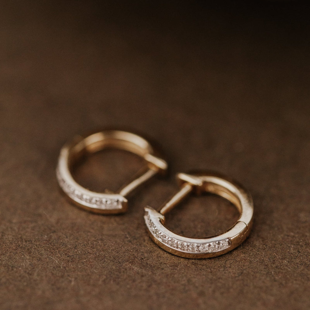 Gold hoop earrings with diamonds on a brown surface