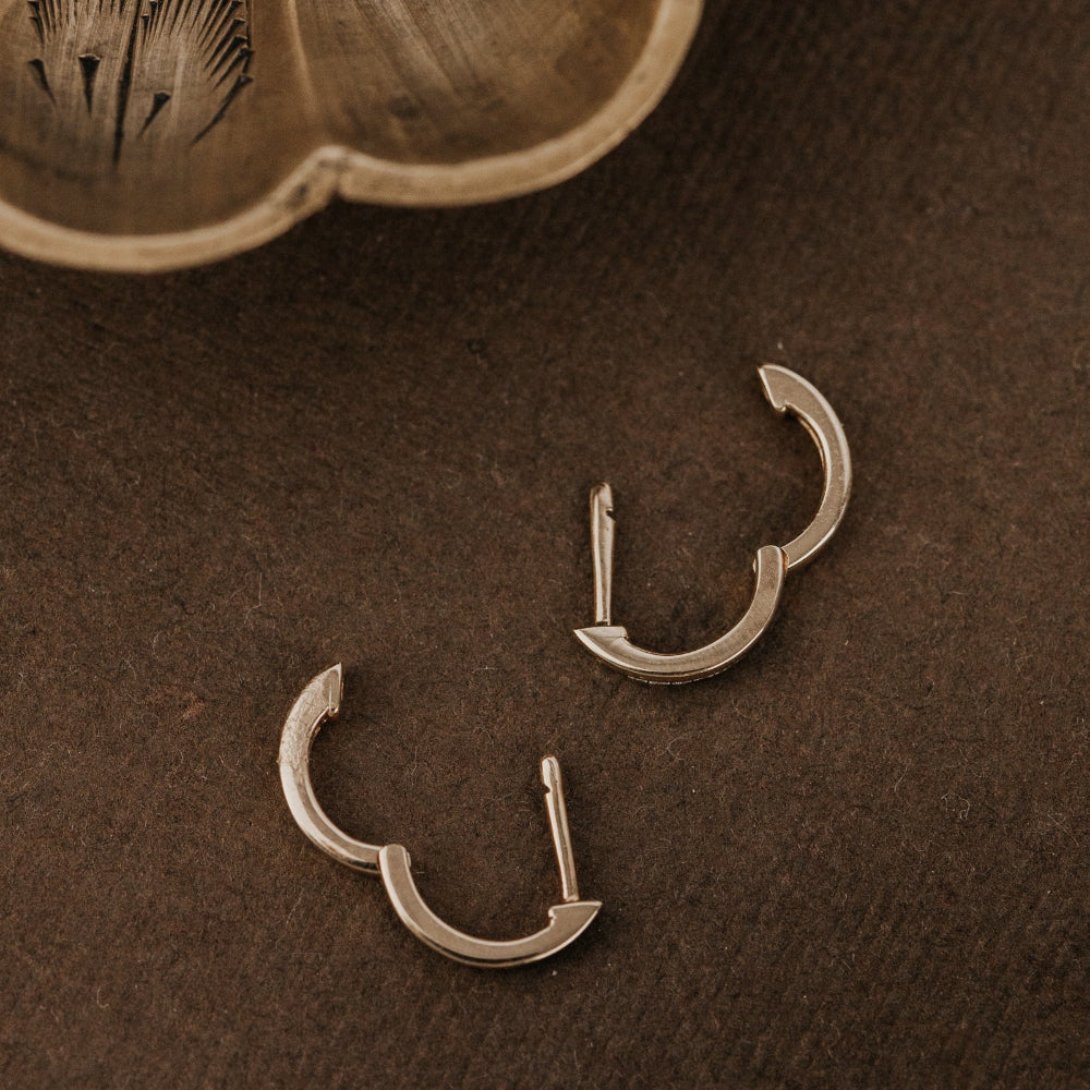 Gold hoop earrings on a brown textured surface.