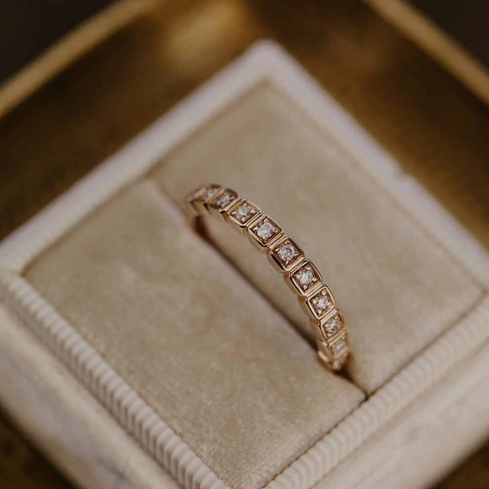Rose gold ring with diamonds in a jewelry box.