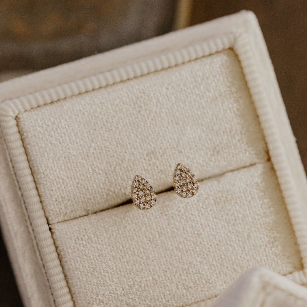 Pair of diamond earrings in a jewelry box with a blurred background.