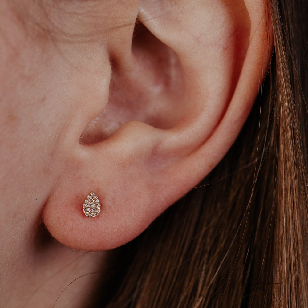 Close-up of an ear wearing a small pave diamond stud earring.