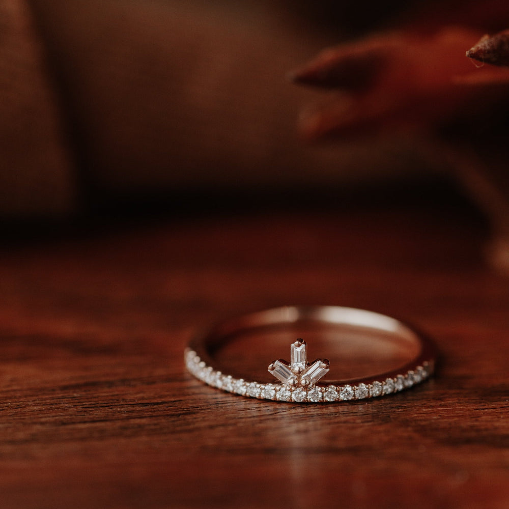 Diamond wedding band on a wooden surface with a blurred background.