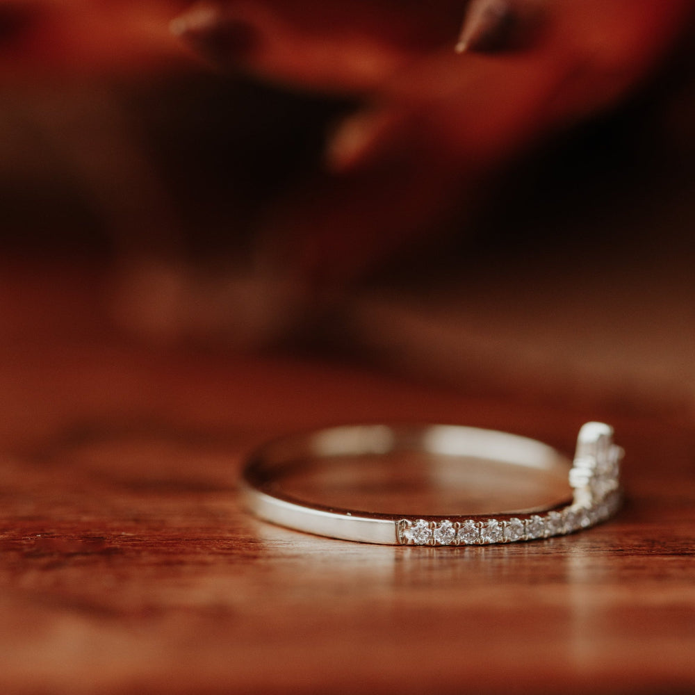 Yellow gold wedding band with small diamonds on a wooden surface.