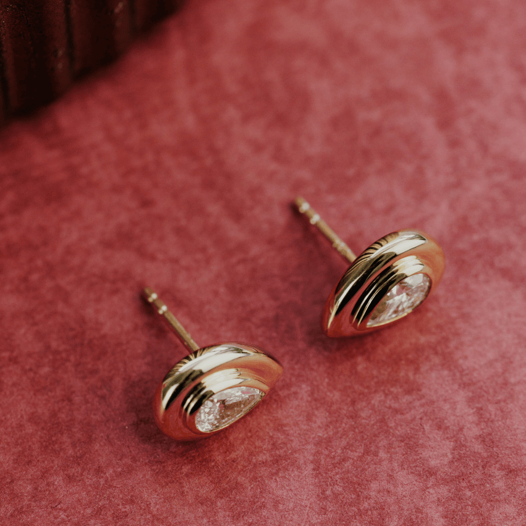 14k gold lab grown diamond earrings showcased on a textured red surface showing the side of the earring. 