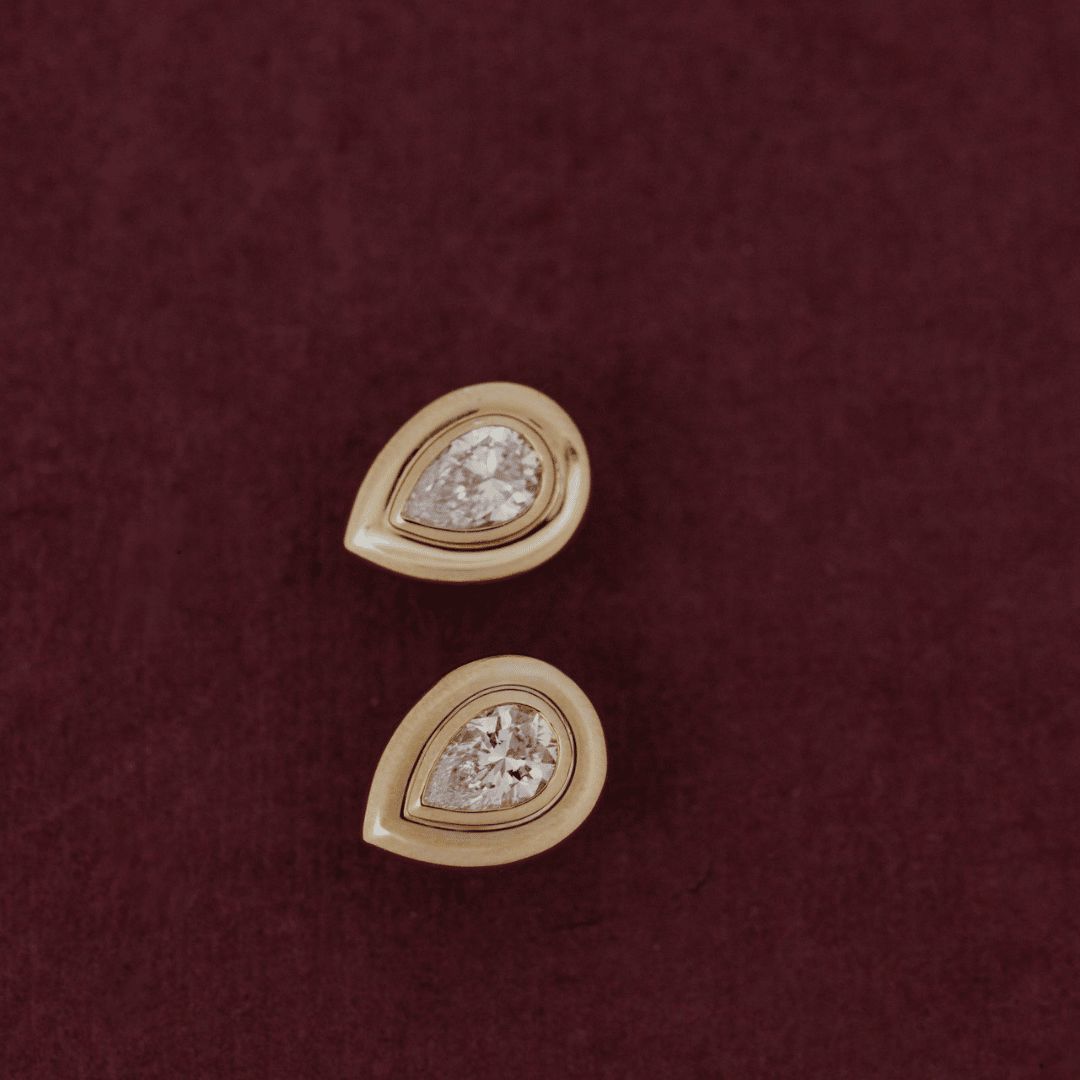 14k gold lab grown diamond earrings showcased on a textured red surface showing the front of the earring. 